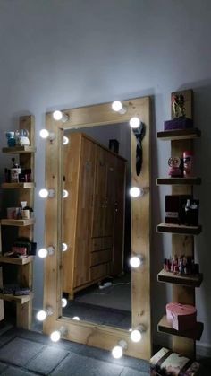 a lighted mirror sitting on top of a wooden shelf next to a dresser and drawers