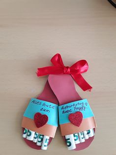 an origami shoe with a red ribbon tied around it on top of a table