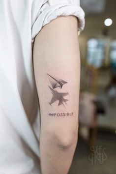 a woman with a tattoo on her arm that says impossible possible and two birds flying in the sky