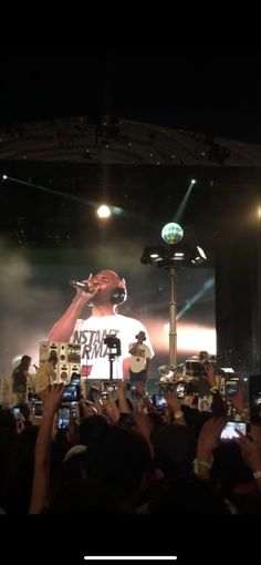 a man standing on top of a stage holding up his cell phone in front of him