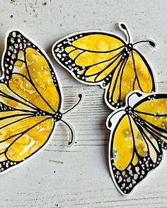 three yellow butterflies sitting on top of a white wooden table with black dots and spots