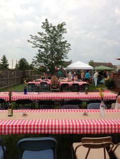 several tables with red and white checkered tablecloths are set up for an outdoor gathering