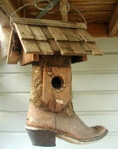 a bird house hanging from the side of a wooden building with a pair of boots on it