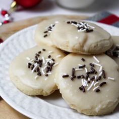 three cookies with white frosting and sprinkles on a plate