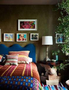 a bedroom with green walls and pictures on the wall above the bed, along with a blue headboard