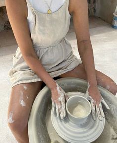 a woman sitting on top of a pottery wheel