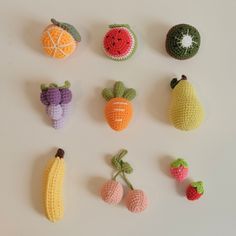 crocheted fruits and vegetables are arranged on a white surface