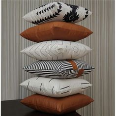 a stack of pillows sitting on top of a wooden table next to a striped wall