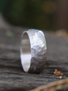 a silver ring sitting on top of a wooden table next to some grass and dirt