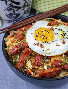 a bowl filled with rice, meat and an egg on top of it next to chopsticks