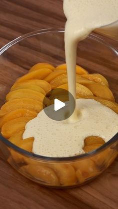 a bowl filled with sliced oranges and cream being poured into it