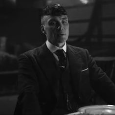 a man wearing a suit and tie sitting at a table in front of a bowl