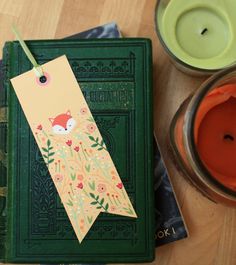 a green book with a fox on it next to two candles and a candle holder