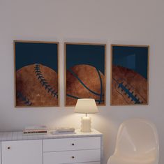 two framed sports pictures hang on the wall next to a white dresser with a lamp