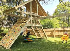 a child playing in a backyard with a wooden climbing wall and play set on the grass