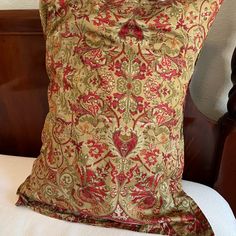 a decorative pillow on top of a white bed in a room with wooden headboard