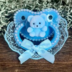 a small blue teddy bear sitting on top of a table next to a bow tie