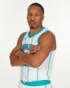 a man with his arms crossed wearing a basketball uniform