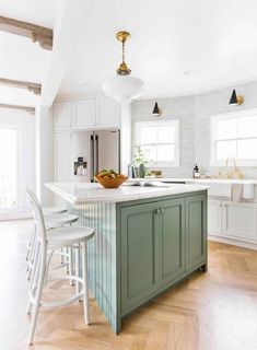 a kitchen with white cabinets and green island in the center, surrounded by bar stools