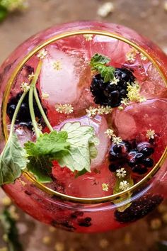 a red drink with blueberries and mint garnish in a glass on a table