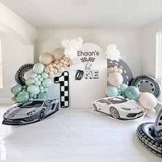 a room filled with balloons and cars on the floor next to a wall that reads 1