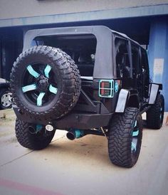 a black jeep parked in front of a building with its tires on it's wheels