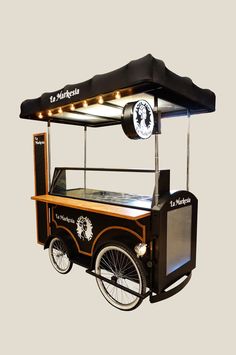 an old fashioned ice cream cart with lights on it's sides and wheels, in front of a gray background