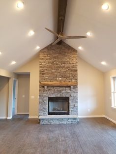 an empty living room with a fireplace and ceiling fan