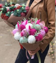 a woman holding two bouquets of flowers in her hands, both with pom poms on them