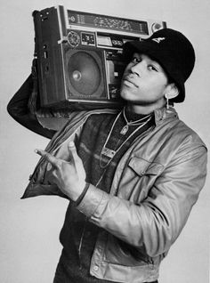 the man is holding an old radio in his right hand and wearing a hat on top of his head