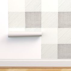 a white and grey checkered wallpaper with a roll of paper on the floor