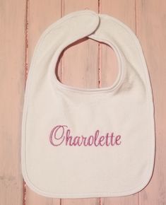 a white bib with the word charlotte embroidered on it sitting on a wooden surface