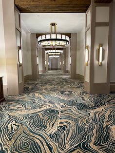 a long hallway with an intricate carpet and chandelier