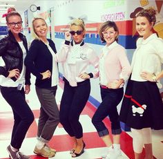 four women are posing for the camera in front of a wall with mickey mouses on it