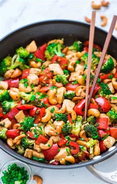 a skillet filled with broccoli, cashews and red bell peppers