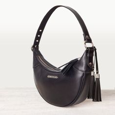 The perfect partner for modern lifestyles, the Elle Half Moon Black Handbag blends equestrian elegance with a sleek, contemporary design. Crafted from luxurious Italian leather with dark tan stitching, this crescent-shaped bag features a wide, adjustable shoulder strap adorned with nickel grommets. The top zipper, complete with a stylish tassel pull, secures a custom interior with zipper pouches and sleeves. Ideal for both stable and city outings, this black leather purse offers EQ Chic and mode Elegant Leather Saddle Bag With Palladium Hardware, Elegant Saddle Bag With Leather Handles For Everyday Use, Leather Shoulder Bag With Palladium Hardware And Round Handle, Elegant Black Smooth Grain Hobo Bag, Leather Shoulder Bag With Smooth Grain And Round Handle, Elegant Saddle Bag With Leather Handles, Classic Leather Hobo Bag With Round Handle, Elegant Leather Hobo Bag With Round Handle, Everyday Shoulder Bag With Smooth Grain And Round Handle