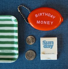 an orange birthday money sitting on top of a table next to two quarters and a coin