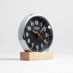 an alarm clock sitting on top of a wooden block in front of a white background