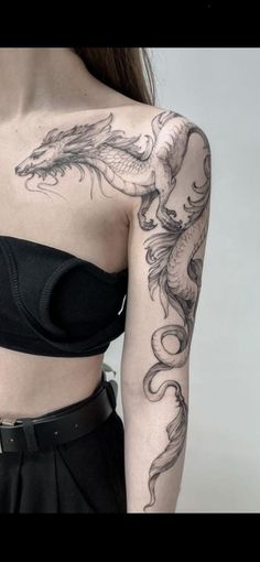 a woman with a dragon tattoo on her arm and shoulder is wearing a black top