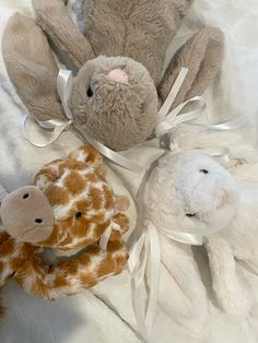 three stuffed animals sitting on top of a white bed sheet with ribbons around them and tied together