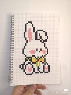 someone is holding up a cross - stitch book with an image of a rabbit on it