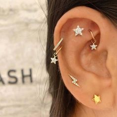 a woman wearing three star ear piercings in gold and silver with diamonds on them