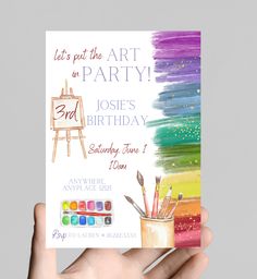 a hand holding up a birthday card with an easel and paintbrush on it