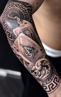 a man's arm with tattoos on it and some playing cards in the middle