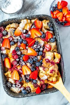 a casserole dish with berries and powdered sugar