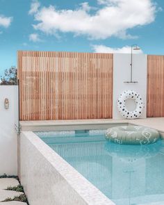 an empty swimming pool with a life preserver in the middle and a wooden fence behind it