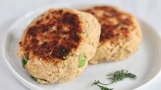 two crab cakes are on a white plate