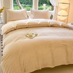 a bed with gingham comforter and two cups on the pillow in front of it