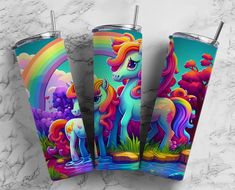 three colorful unicorn tumblers sitting next to each other on a marble counter top with rainbows and clouds in the background