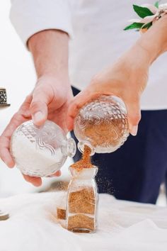 a person pouring sand into a glass bottle